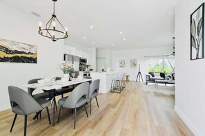A modern kitchen with white cabinetry, a dining area with grey chairs, and a chandelier. - Beautiful, modern and new Home (Port Charlotte)