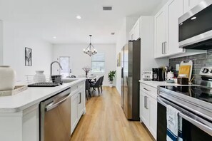 A modern kitchen with white cabinetry, stainless steel appliances, and a central island.