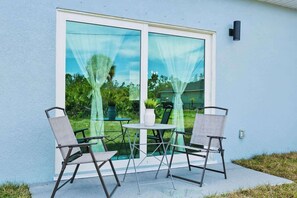 A patio with two chairs and a table, a sliding glass door, and a small potted plant. - Beautiful, modern and new Home (Port Charlotte)