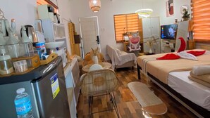 Een kleine hotelkamer met kitchenette, een bed, een zithoek en een televisie.