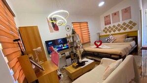Een moderne hotelkamer met een televisie, een bed met handdoeken in de vorm van hartjes, een bureau en een sofa.
