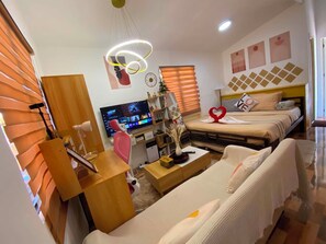 A modern hotel room with a TV, a bed with heart-shaped towels, a desk, and a sofa. - Cozy Studio-type bungalow in welcoming Olango island, Lapu-lapu City with AC (Lapu-lapu City)