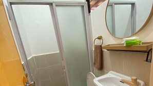 Een badkamer met toilet, wastafel, spiegel en een douchedeur.