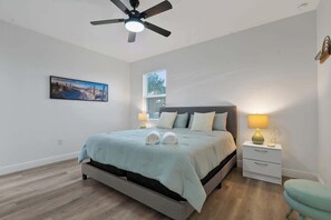 Ein Schlafzimmer mit einem Bett, Nachttischlampen, einem Deckenventilator und einem Fenster.