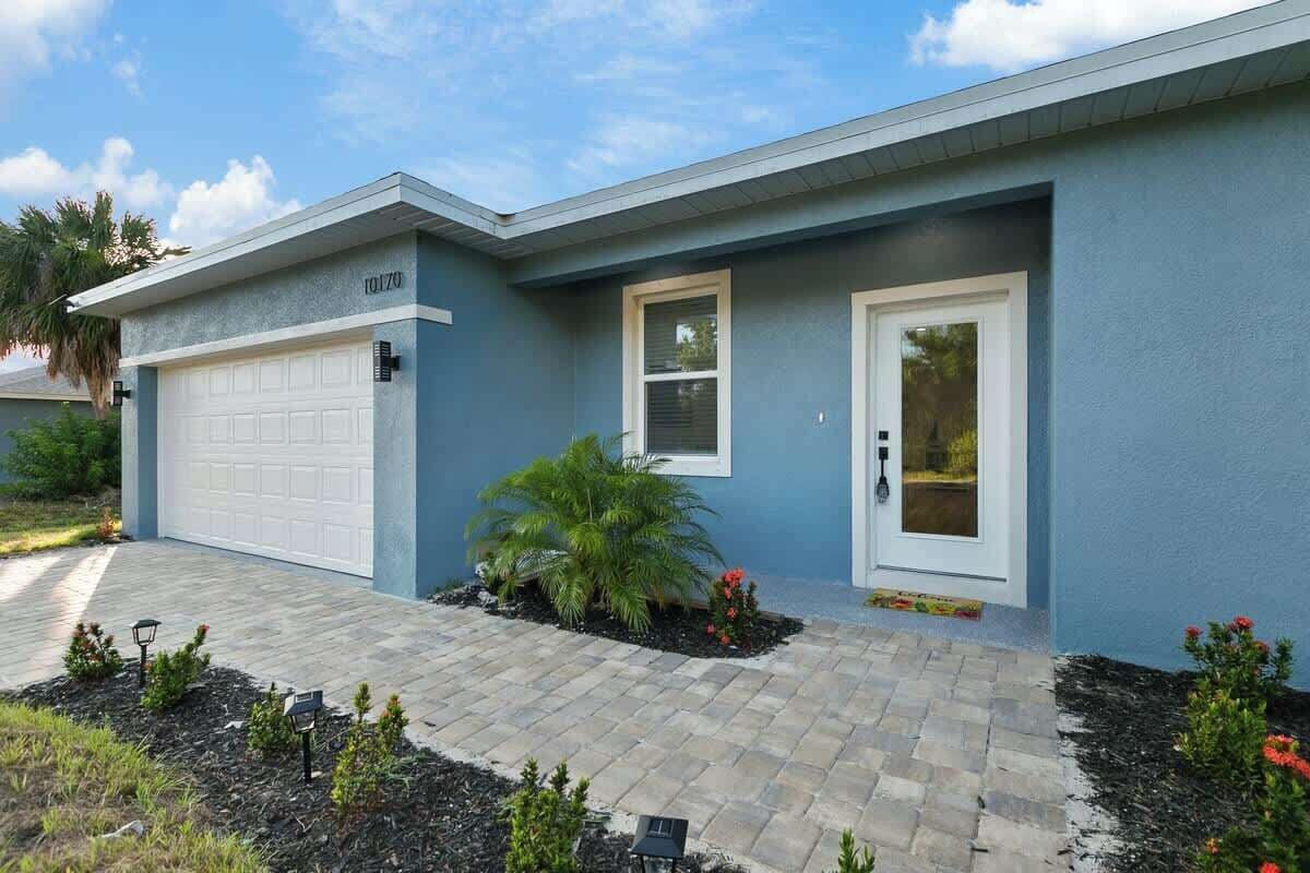 A modern two-story house with a garage, a front door, and a small window.