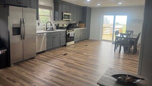 A modern kitchen with grey cabinets, stainless steel appliances, and a wooden floor. -  Sea La Vee Waterfront 4BR Retreat in Buxton, NC (Buxton)