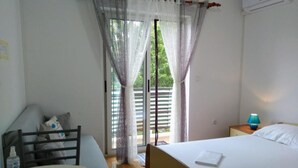 A bedroom with a bed, a desk, a chair, a nightstand, a lamp, and a window with curtains. - Room Amor (Rovinj)