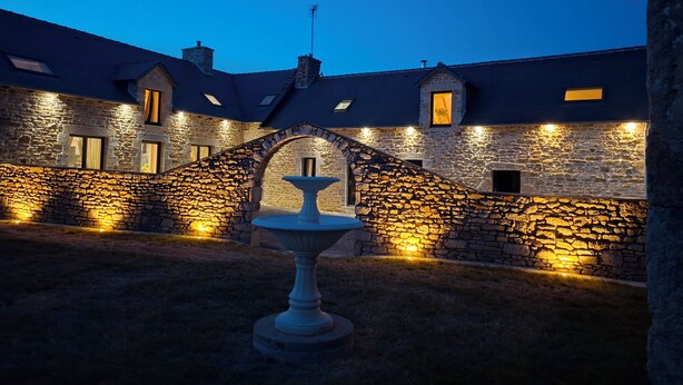 A stone building with a central archway and a fountain in the courtyard. - Vacation Rental 2: "La Belle Aire" at Christophe's (Le Fœil)