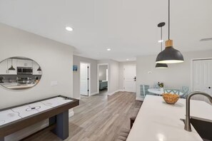 A modern kitchen with a dining area, a mirror, and a pendant light.