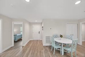 A room with a round dining table, chairs, a bed, and a door.