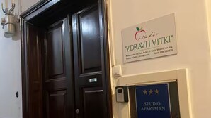 A dark wooden door with a sign above it reading 'ZDRAVI VITKI' and a blue sign below stating 'STUDIO APARTMAN'. - Camera Munz (Pula)