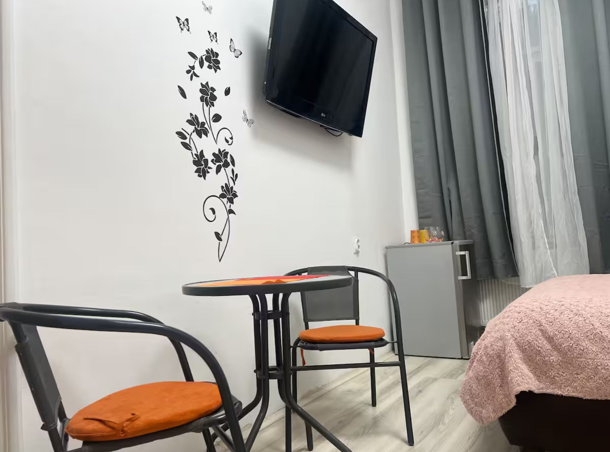 Ein Hotelzimmer mit Bett, Fernseher, einem kleinen Tisch, zwei Stühlen und einer dekorativen Wandsticker.