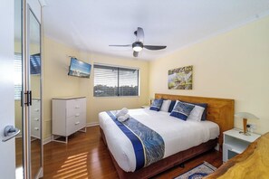 A bedroom with a bed, a ceiling fan, a window with blinds, a dresser, and a painting on the wall. - Sweeping Marina Views | Pool + Balcony | Sleeps 4 (Urangan)