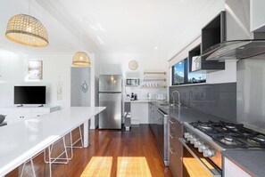 Uma cozinha moderna com ilha central, eletrodomésticos de aço inoxidável e iluminação pendente.