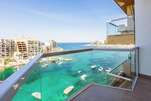 A balcony with a clear view of the sea, boats, and buildings. - Modern 2 Bedroom Seafront Escape (Saint Julian's)