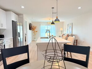 A modern kitchen with white cabinets, a central island, and pendant lighting.