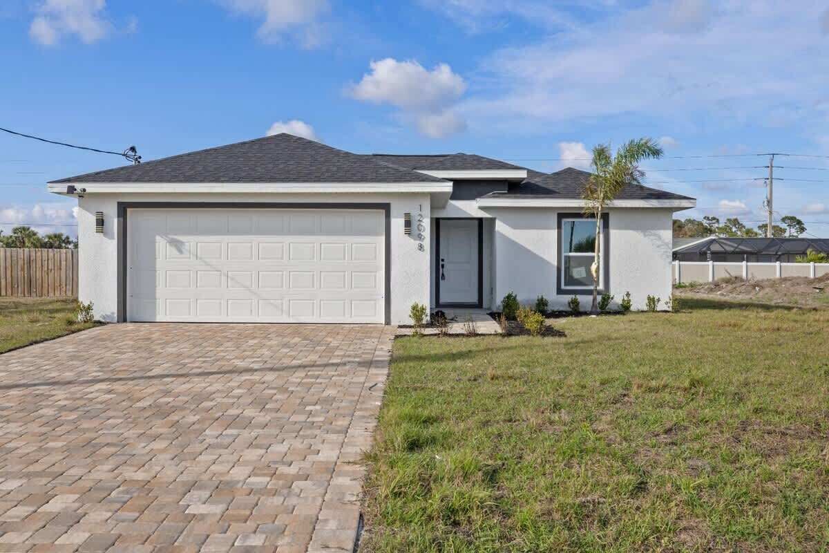A single-story house with a garage, a small front porch, and a brick driveway.