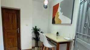 A dining area with a wooden table and chairs, a potted plant, and a modern painting on the wall. - Cozy 1-bedroom apartment with terrace in Dakar (Dakar)