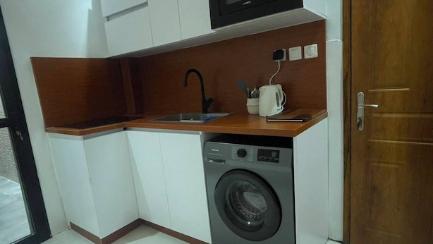 A compact kitchen with a washing machine, a microwave, and a coffee maker. - Cozy 1-bedroom apartment with terrace in Dakar (Dakar)