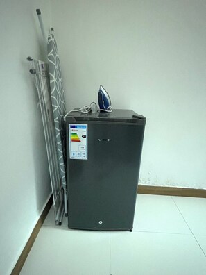 A compact, dark-colored refrigerator with a control panel on the front, positioned against a plain wall with a tiled floor. - Cozy 1-bedroom apartment with terrace in Dakar (Dakar)
