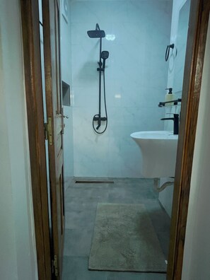 A bathroom with a shower, sink, and a towel on the floor. - Cozy 1-bedroom apartment with terrace in Dakar (Dakar)