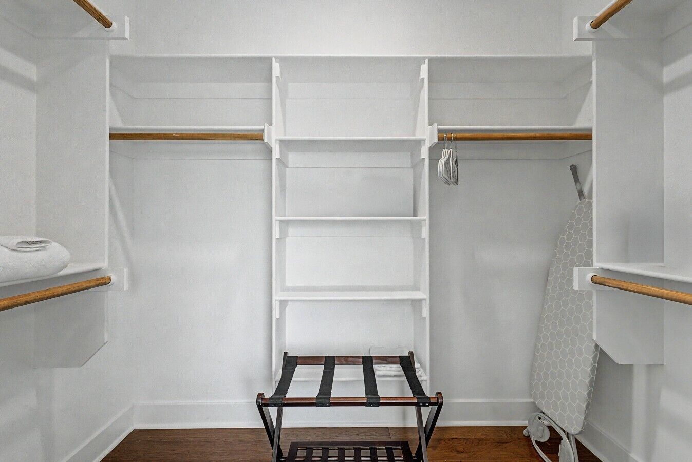 A walk-in closet with open shelving, a wooden rack, and a hanging towel rack.