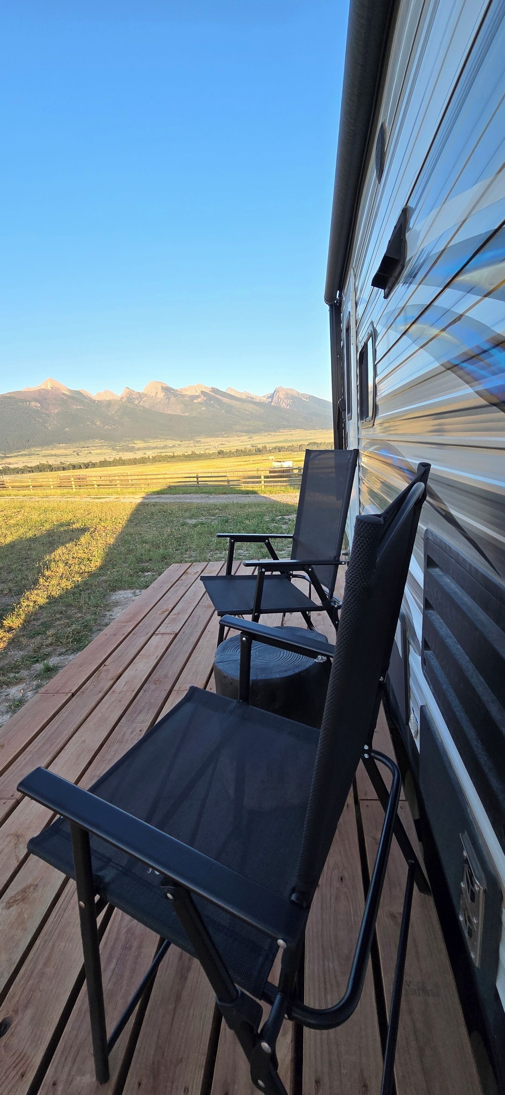 Eine Terrasse mit zwei Stühlen und einem Tisch mit Blick auf eine Berglandschaft.