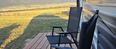 A deck with two chairs and a table, overlooking a mountainous landscape.
