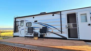 A recreational vehicle with a deck, a table, and chairs.