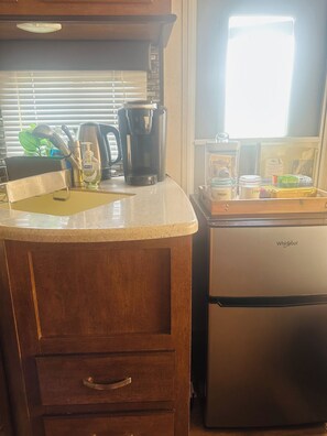 Een keuken met een aanrecht, een koffiezetapparaat, een waterkoker en een koelkast.