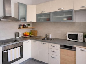 A modern kitchen with a stove, microwave, sink, and cabinets. - Ljubelle Premium Stay (Seget)