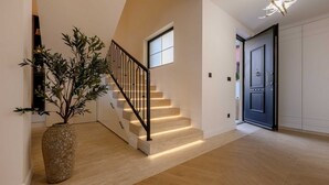 Eine Treppe mit Holzdielen und einem schwarzen Geländer, ein Blumentopf und eine Tür mit Griff.