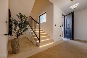 Eine Treppe mit Holzdielen und einem schwarzen Geländer, ein Blumentopf und eine Tür mit Griff.