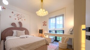 Ein Schlafzimmer mit Bett, Schreibtisch, Stuhl, Fenster und Wandbild.