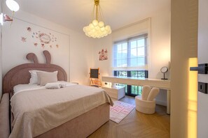 Ein Schlafzimmer mit Bett, Schreibtisch, Stuhl, Fenster und Wandbild.