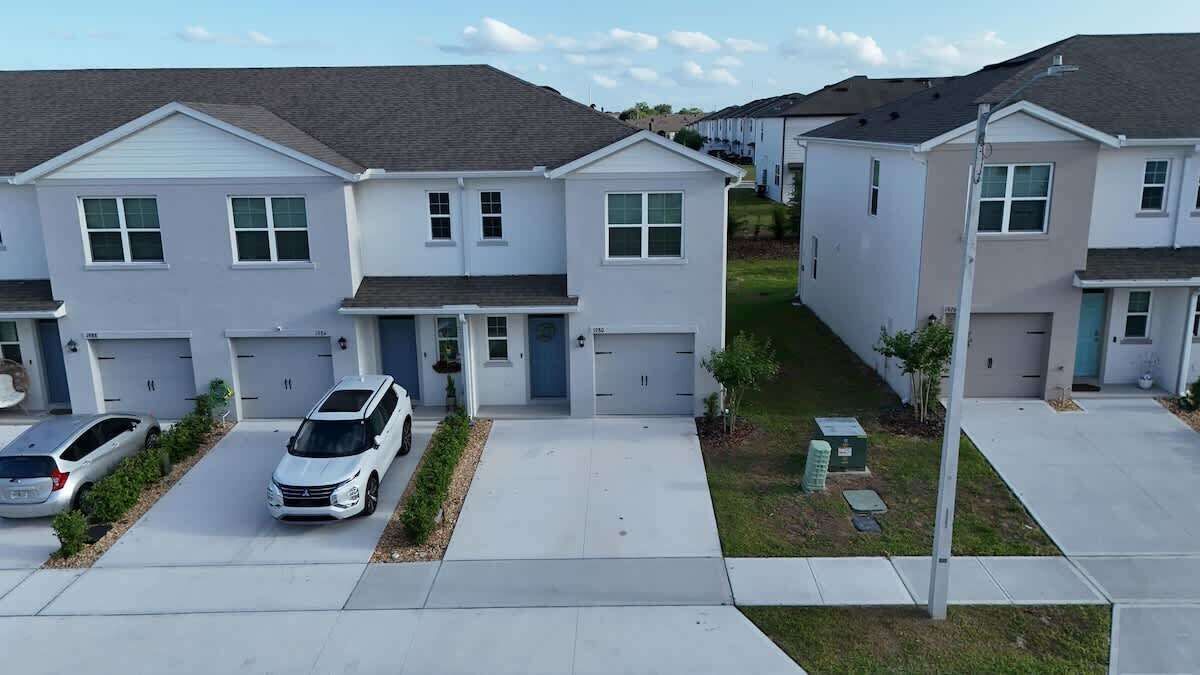A row of townhouses with attached garages, a clear driveway, and a small lawn area.