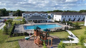 Una zona residencial con piscina, parque infantil y una fila de casas adosadas.