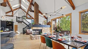Un comedor espacioso con una mesa larga, sillas coloridas y una chimenea de piedra.