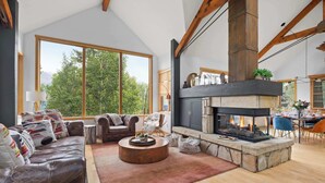 Amplia sala de estar con chimenea, ventanas grandes y techo alto.