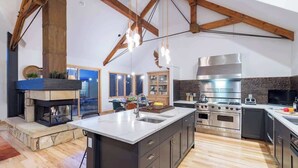 Una cocina amplia con una isla grande, electrodomésticos modernos y una chimenea de piedra.