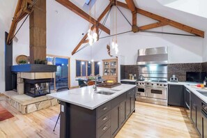 Une cuisine spacieuse dotée d’un grand îlot central, d’appareils électroménagers modernes et d’une cheminée en pierre.