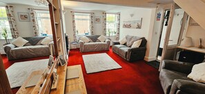 A spacious living room with two sofas, a coffee table, and a red carpet. - 19 Newtown Sidmouth is a Cosy Cottage and Family Home 600m to Beach (Sidmouth)