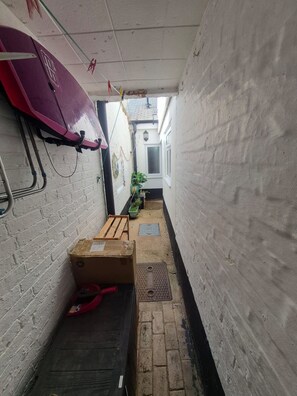 A narrow hallway with a bench, a surfboard, and a potted plant. - 19 Newtown Sidmouth is a Cosy Cottage and Family Home 600m to Beach (Sidmouth)