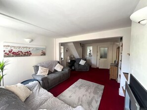 A living room with a grey sofa, a red carpet, and a painting on the wall. - 19 Newtown Sidmouth is a Cosy Cottage and Family Home 600m to Beach (Sidmouth)
