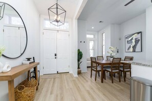 A modern interior with a dining area, white walls, and a large mirror. - Modern &Historic Northwest Charm (Washington)