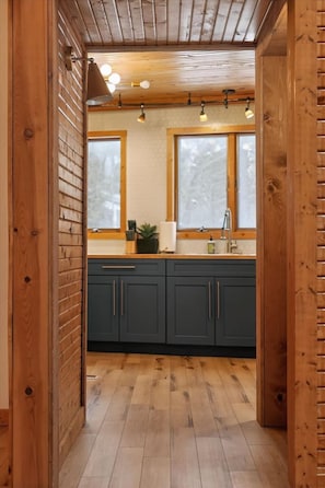 A wooden interior with a kitchen area, including cabinets, a sink, and a window.