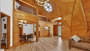 Un loft amplio con pisos de madera, un comedor y una cama en zona alta.