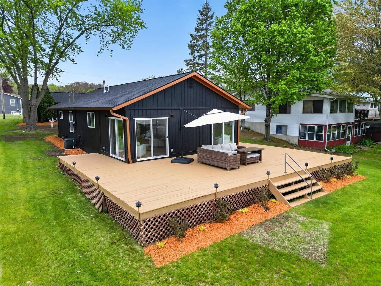 Une maison moderne dotée d’une terrasse, d’un espace salon extérieur et d’une grande fenêtre.