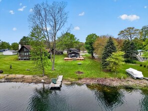 Une propriété au bord du lac, comprenant un quai, une maison et un bateau abrité.