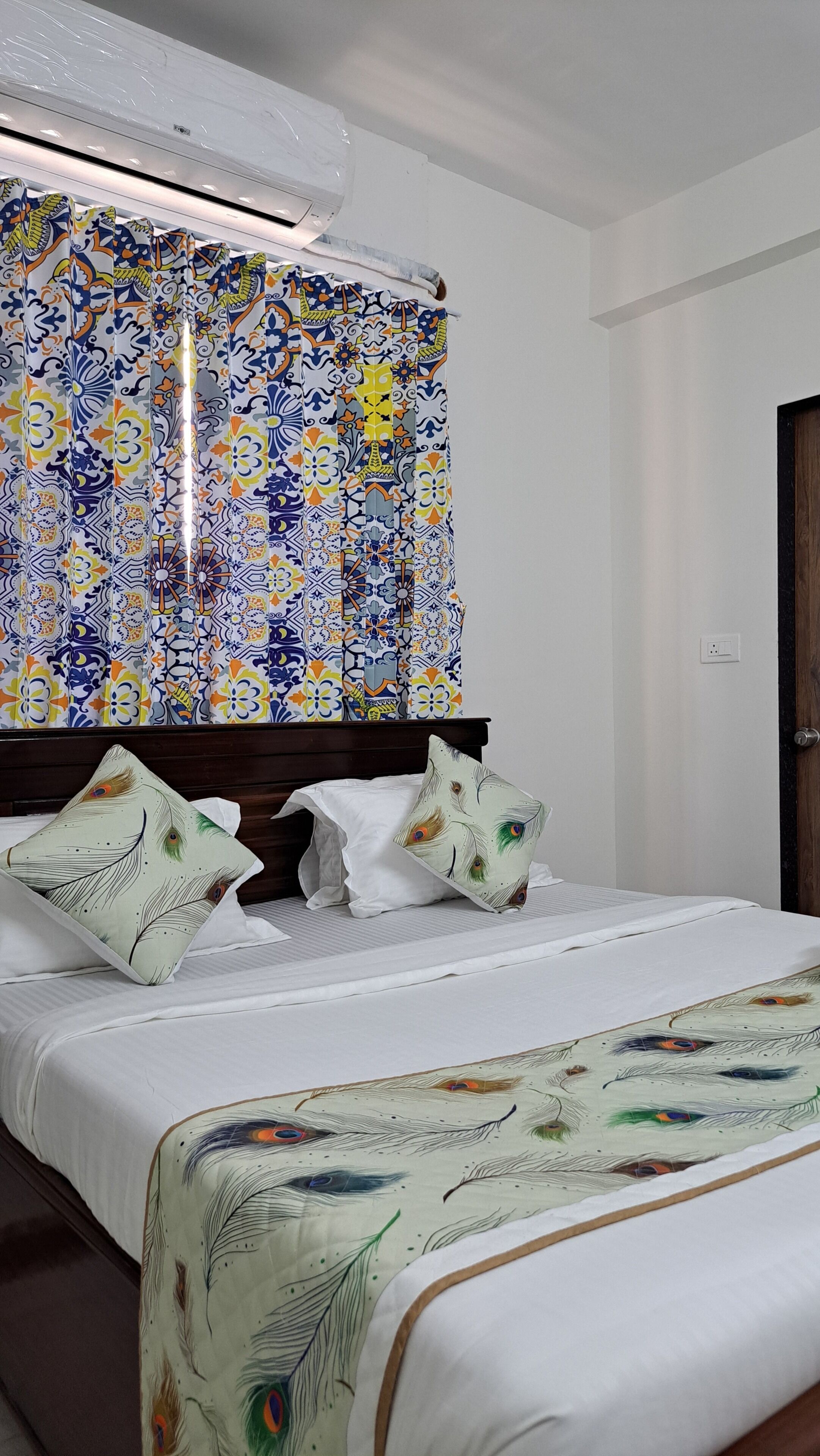 Una habitación de hotel con cama, almohadas y cortina con diseño colorido.